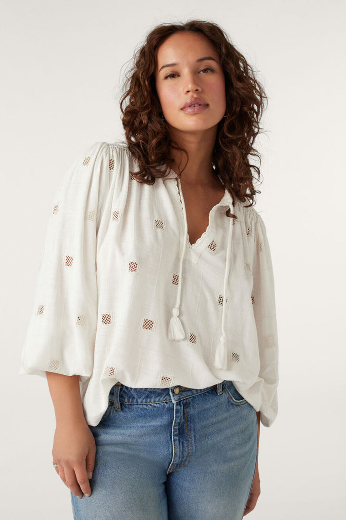 The Ravel Blouse by Ba&sh is an elegant openwork top that features tone-on-tone embroidery and an embellished v-neckline. The sleeves are long and the ties at the neckline are finished with tassels creating a bohemian feel. Wear with jeans or a maxi skirt for an easy everyday look.