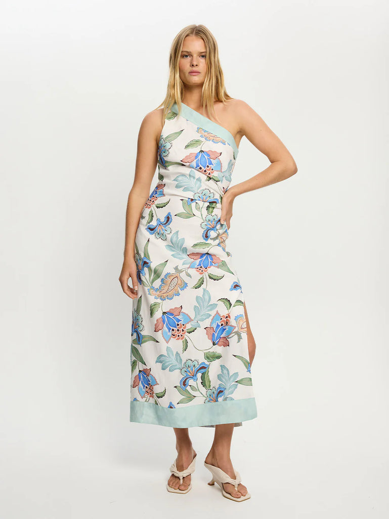 This gorgeous midi dress is crafted from a beautiful European flax linen in a bold print featuring striking blue blossoms, terracotta accents and green leaves on a lovely crisp white base.&nbsp; Featuring a sexy asymmetric neckline and adjustable shoulder tie, a side slit, contrast mint along neckline and the hem and a body skimming fit this is perfect for lovely long lunches and elevated evening occasions.