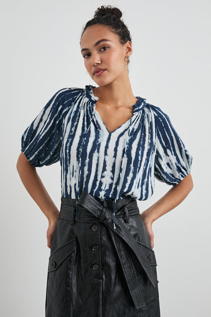 This pretty little top from Rails is perfect as a transitional piece.&nbsp; In a dip dye-ish indigo and white stripe and featuring a flattering v neck, puffy elasticated short sleeves and a ruffle detail at the neck Laila looks fab paired with your favourite denim.