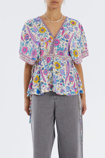 The Raven Top from Lollys Laundry features a v-neckline at the front and back and a pretty string tie with tassels at the back.  It has short, loose fit sleeves and comes in a colourful, floral, summery print.   Easily dress this top up or down with a jean or smart trouser.
