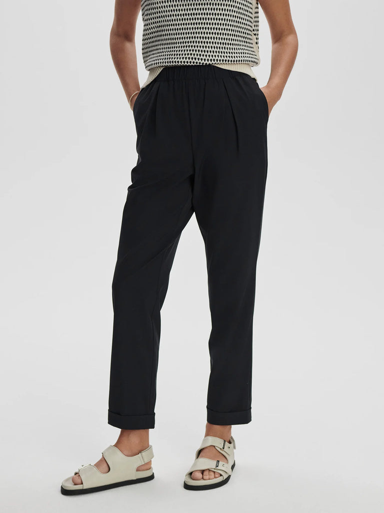 The Varley Alana Slim Tapered Cuff Trousers are crafted from their Soft Stretch Woven Fabric. They are extremely lightweight and a slim tapered fit with an elasticated waistband, pleated front and turn-up cuffs. Pair with your favourite t-shirt or sweatshirt, perfect for all-day comfort.