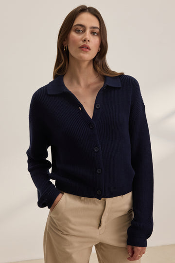 The Taj Cardigan is a super soft cotton knit from Velvet by Graham &amp; Spencer. In an easy to wear navy, this pullover features a preppy/sporty collar and long sleeves. This is perfect paired with your favourite skirt or denim!