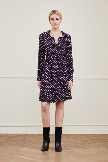 Pretty little shirt dress from Fabienne Chapot.  In a feminine navy print with pink hearts this knee length dress has a lovely flirty feel about it.  Featuring a buckle fabric tie at the waist and a flouncy hem pair this with your favourite boots and a leather jacket for an evening out.