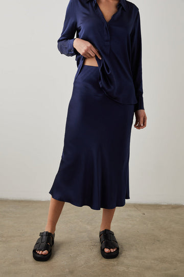 Super silky luxury satin crepe sleek midi skirt in always flattering navy. Featuring a concealed elastic waist and extremely flattering bias cut this is a skirt you'll reach for again and again.  Pair with the Rails Ellis in Indigo tied at your waist with white trainers for an easy day look or pair with a silky cami and heels for the evening.  One you'll reach for again and agian.