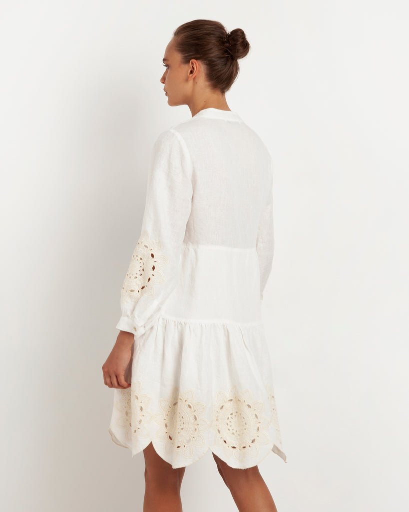 This stunning dress from Greek Archaic Kori has a v-neckline, long sleeves and button front to the hem. It has a tiered skirt featuring beautiful ecru daisy embroidery which is also on the sleeves.   Available in store in white with blue embroidery.