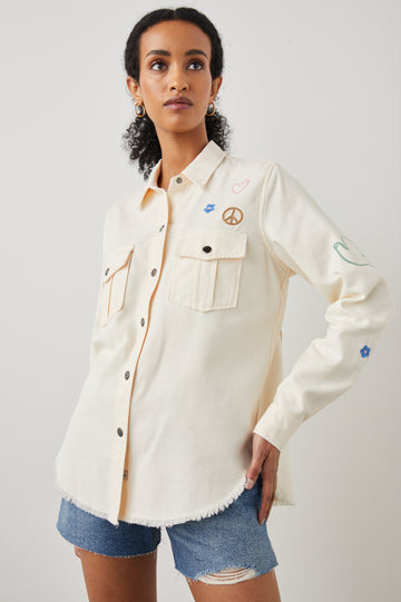 This vintage twill, long sleeve, button-down shirt jacket from Rails features embroidery motifs, flap pockets with button closure at the chest and a raw hem. This staple is easy to wear open with a tee for a laidback look or buttoned-up for classic styling.  This season in a flattering ivory this is perfect paired with your favourite denim shorts.
