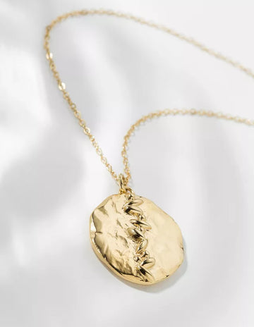 This medal necklace from Louise Damas is made of brass and tin, gilded with 24k fine gold. From its oversized dimensions to its raw look adorned with delicate patterns, the Jane medal explores all contrasts. All Louise Damas' creations are handmade in their Paris workshop. 