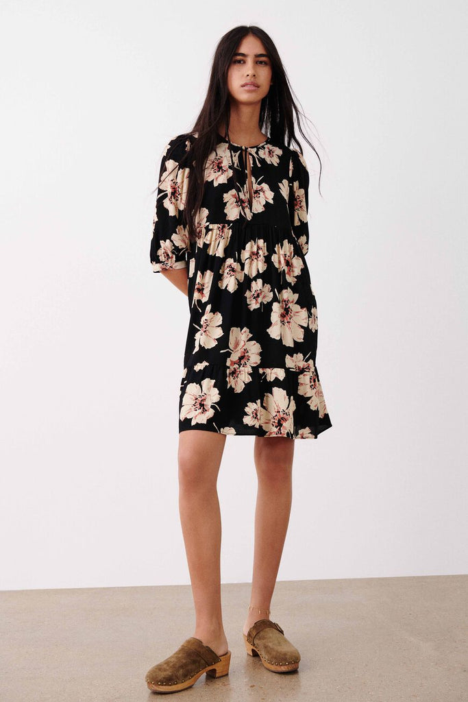 The Katia dress by Ba&sh is short, loose-fitting, features a round neck with a teardrop cut-out fastened with a tie and elbow-length sleeves. The upper panel gathers under the bust and has a flouncy frill at the bottom of the skirt. The flowing fabric holds a bold floral print that is perfect for this season.