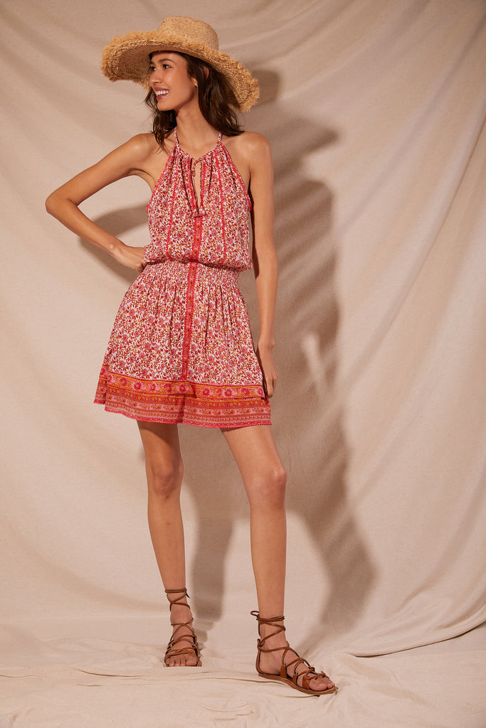 This feminine Carine mini dress from Poupette St Barth features a deep V-neckline, bordered by a pretty pink crochet that continues onto the middle of the dress. Featuring slightly pleated details, a pink floral print and an adjustable tie at the neck, this is the perfect summer dress for any occasion. 