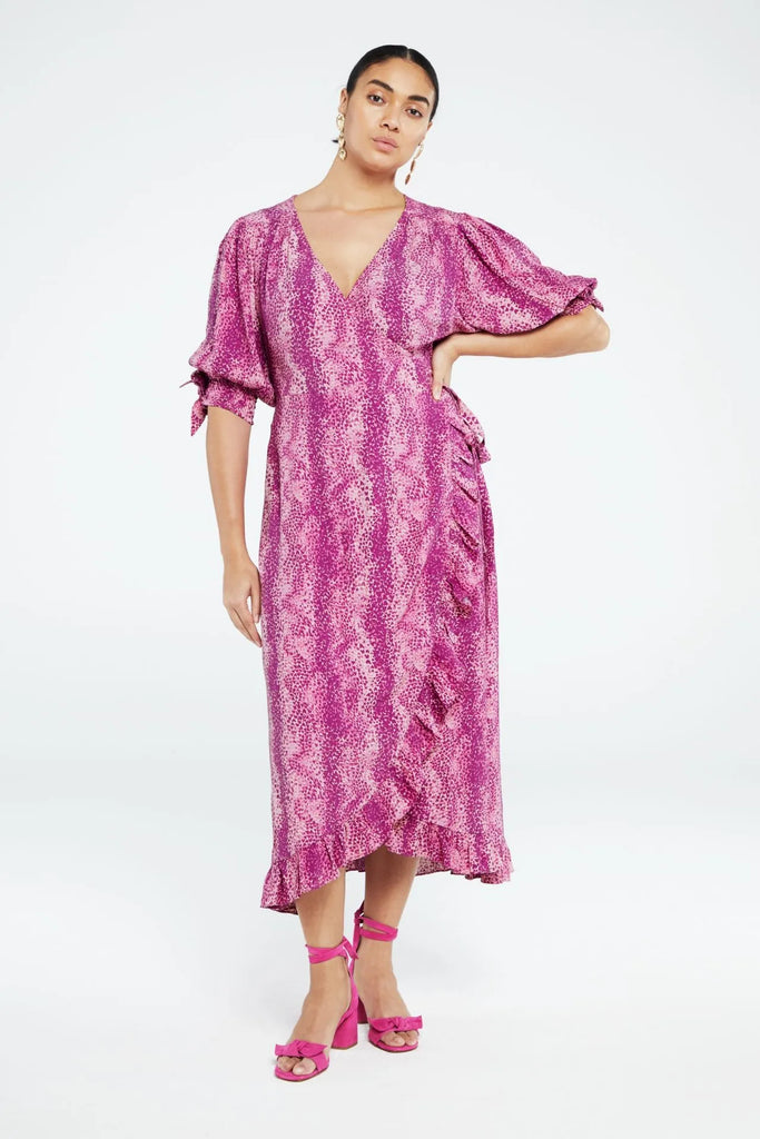 This shawl wrap dress from Fabienne Chapot features ruffles, three-quarter length sleeves and elastic cuffs with bow. The Channa Dress has a v-neckline with snap button and an all over snake print in a fun feminine hot pink.
